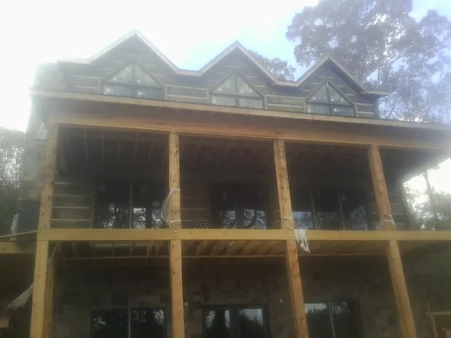 Dormers and porch framing on a large log home under construction — Roof Coating work by our crew in Sussex