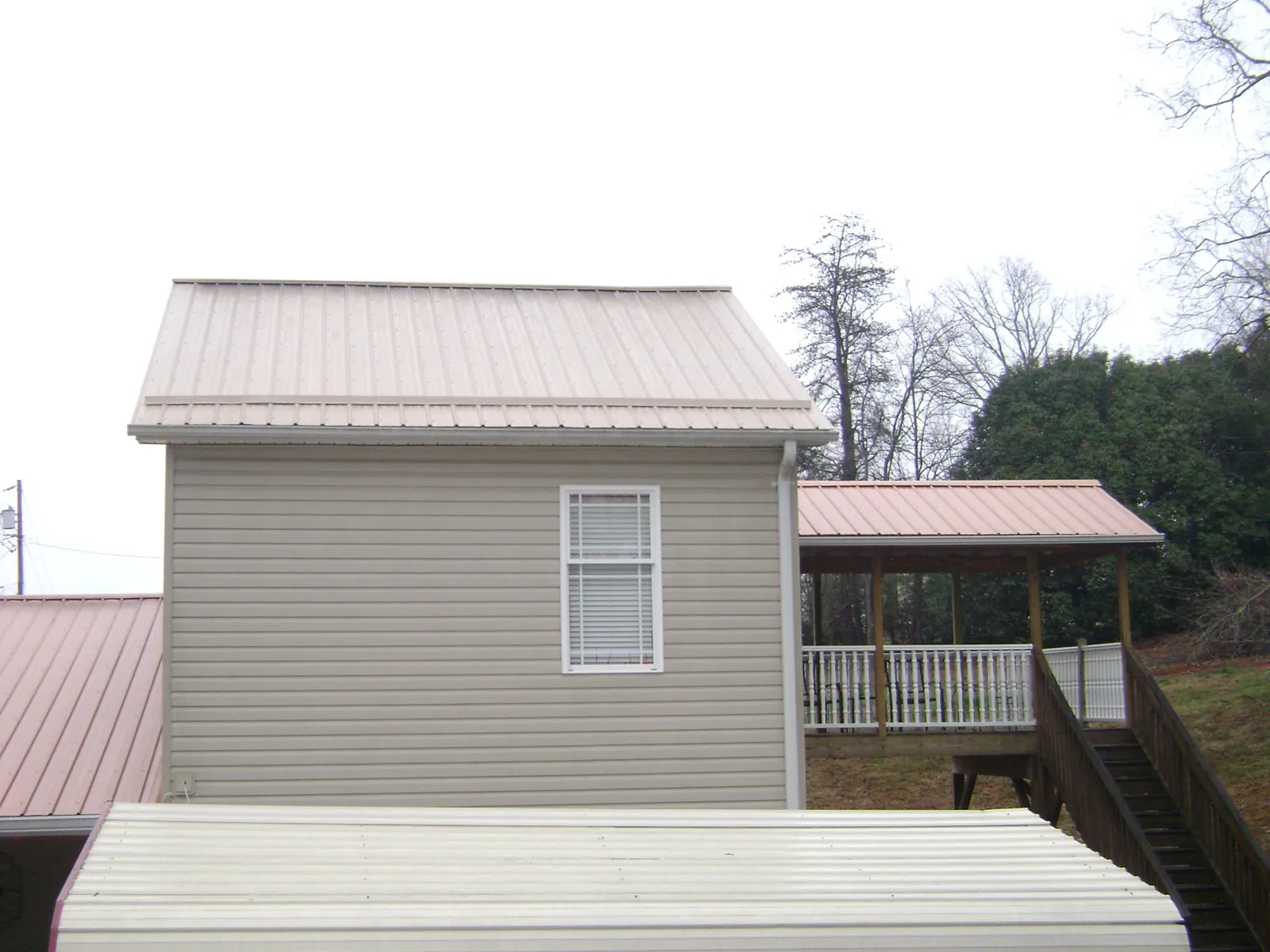 Tan metal roofs on a two story addition and attached porch, from a Roof Replacement job in Sussex